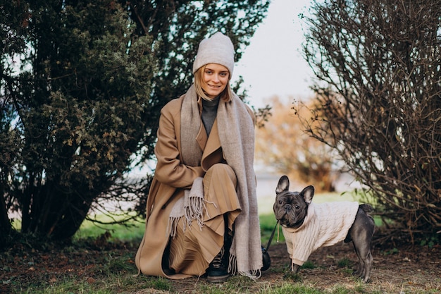 Schöne Frau mit französischer Bulldogge gehend in Park