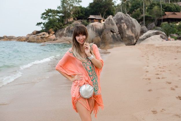 Schöne Frau mit langen Haaren im stilvollen Boho-Sommerkleid, das im tropischen Strand aufwirft.