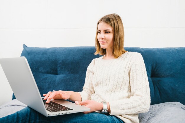 Schöne Frau mit Laptop auf dem Bett