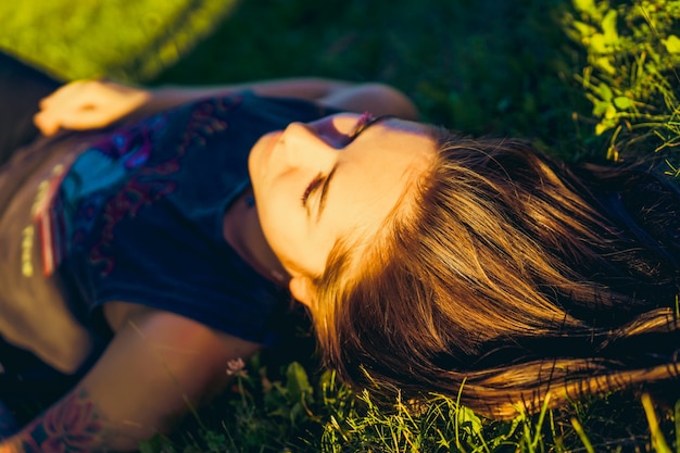 Kostenloses Foto schöne frau mit roten haaren liegt auf grünem gras