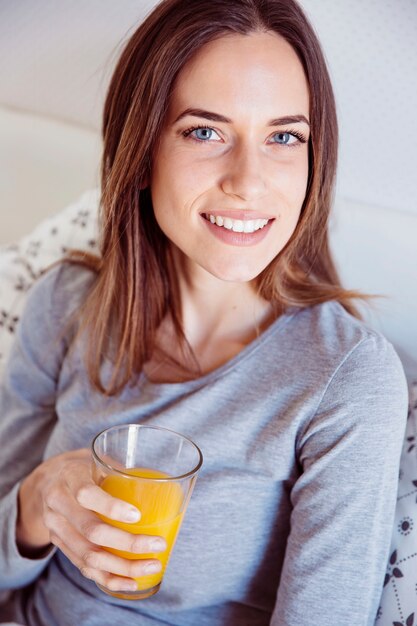 Schöne Frau mit Saft im Bett