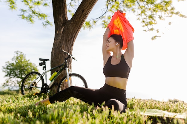 Kostenloses Foto schöne frau mit schmaler passform, die morgens im park auf yogamatte sport treibt