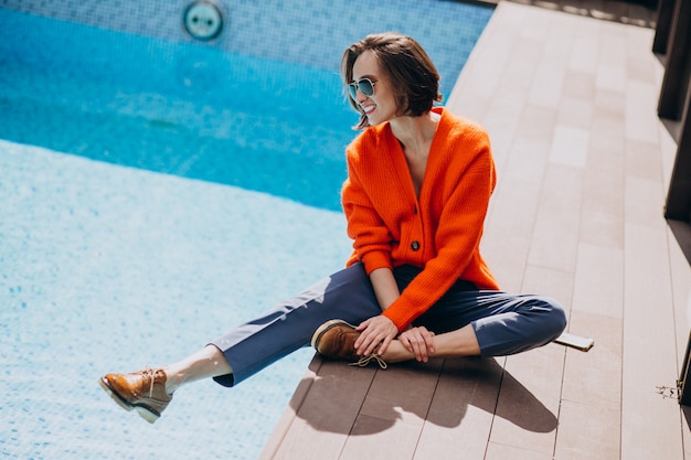 Schöne Frau mit Telefon am Pool sitzen