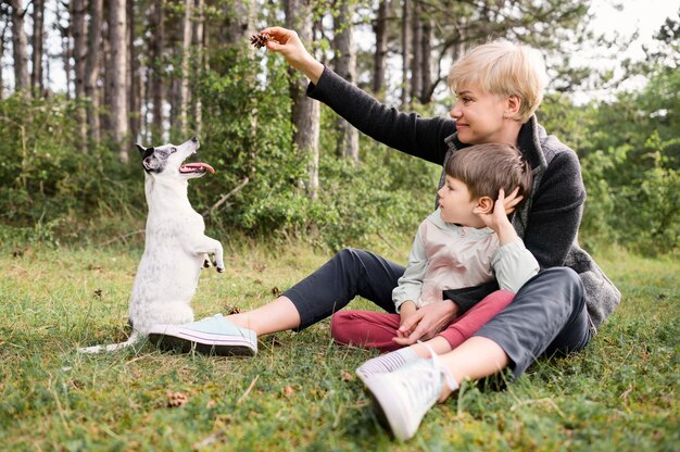 Schöne Frau und kleiner Junge, die mit Hund spielen