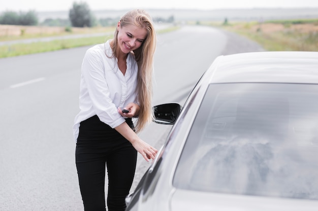 Schöne Frau, welche die Tür des Autos öffnet