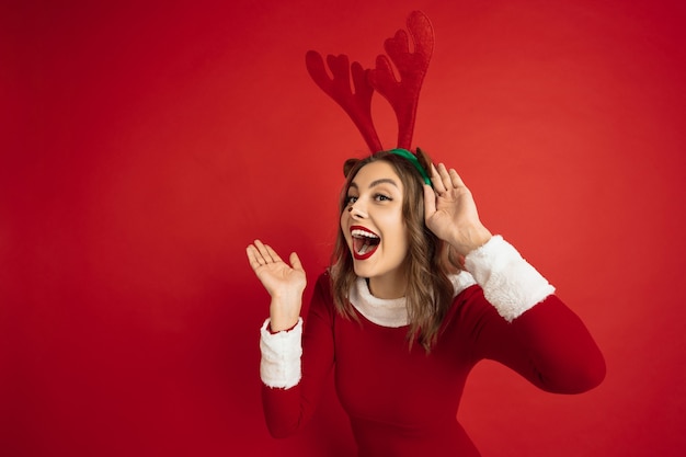 Schöne Frau wie Weihnachtshirsch isoliert auf roter Wand