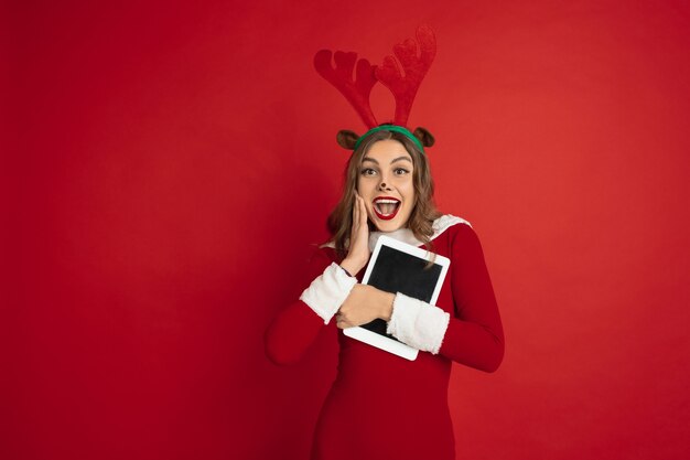 Schöne Frau wie Weihnachtshirsch lokalisiert auf rotem Wandkonzept