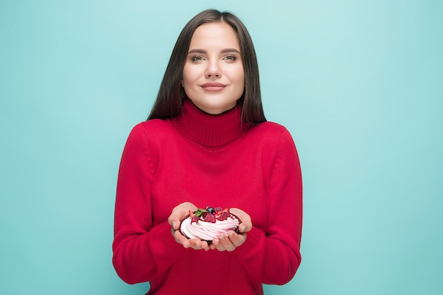 Schöne Frauen, die kleinen Kuchen über blauem Hintergrund halten