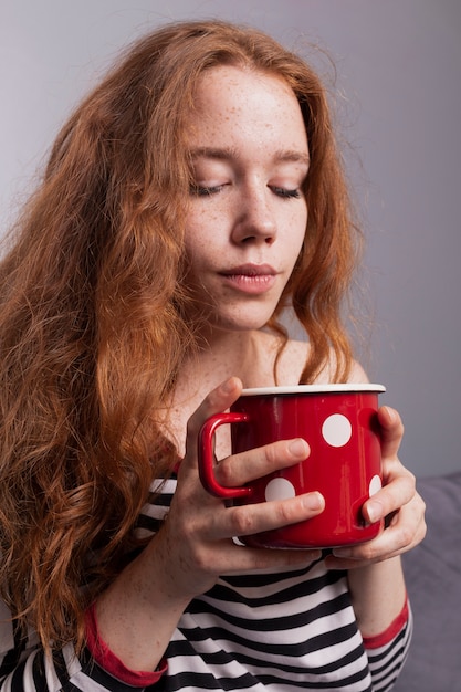 Schöne frekles Frau, die Tasse Kaffee genießt