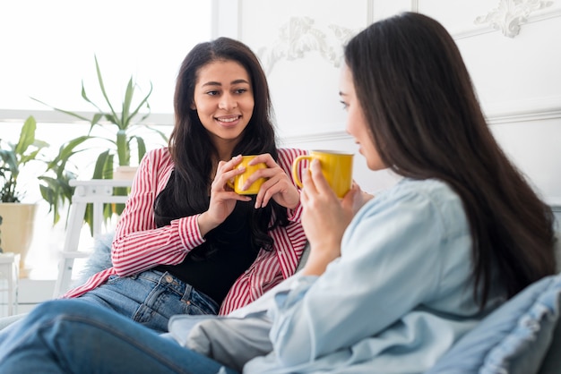 Schöne Freundinnen, die heißes Getränk sprechen und haben