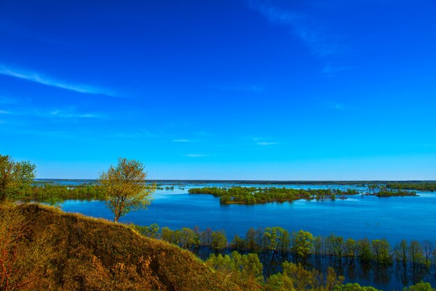 Schöne Frühlingslandschaft. Erstaunliche Aussicht auf die Fluten vom Hügel. Europa. Ukraine. Beeindruckender blauer Himmel mit weißen Wolken