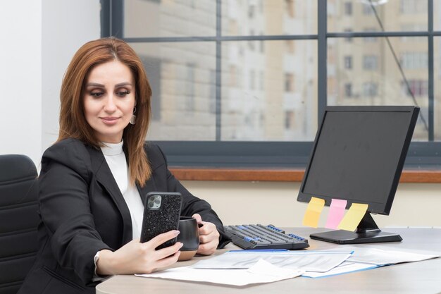 Schöne Geschäftsfrau, die im Büro sitzt und sich selbst macht