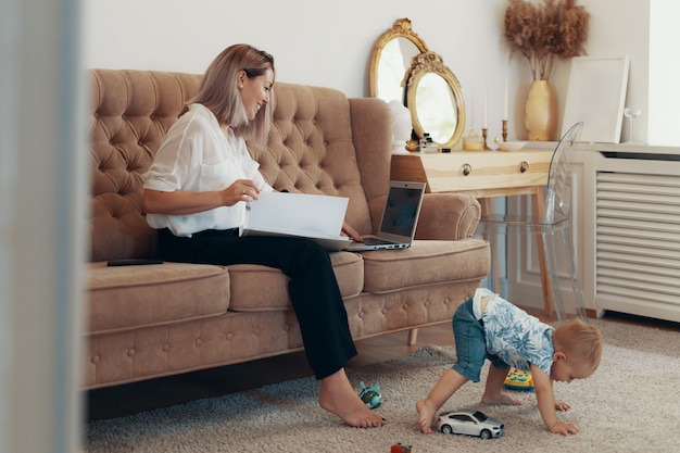 Schöne Geschäftsfrau, die zu Hause arbeitet. Multitasking-, Freiberufler- und Mutterschaftskonzept