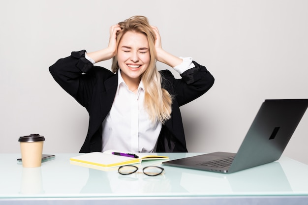 Kostenloses Foto schöne geschäftsfrau erschrocken, erschrocken sitzend am schreibtisch arbeiten unter verwendung des laptops, der bildschirm betrachtet, lokalisiert über weißer wand