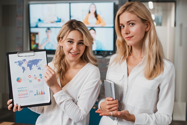 Schöne Geschäftsfrauen, die eine Zwischenablage halten