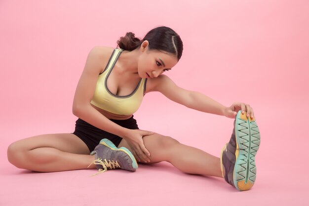 Schöne gesunde junge asiatische Frau, die eine ausdehnende Übung tut, bevor ein Sport gespielt wird.