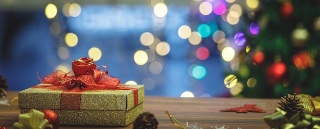 Schöne goldene geschenkbox mit erstaunlicher schleife unter fantastischem buntem bokeh-licht der weihnachtsfeier für den dezember-feiertag des neujahrsfests. fügen sie etwas rauschen hinzu, um das bild im vintage-stil anzupassen.