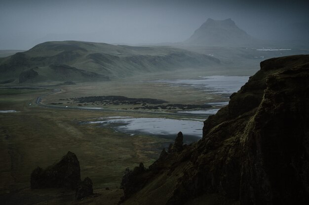 Schöne grüne Landschaft mit einem See, umgeben von hohen Bergen, die von Nebel umhüllt sind