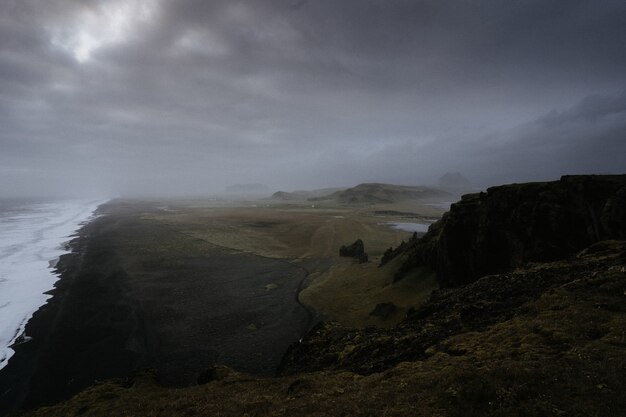 Schöne grüne Landschaft mit einem See, umgeben von hohen Bergen, die von Nebel umhüllt sind