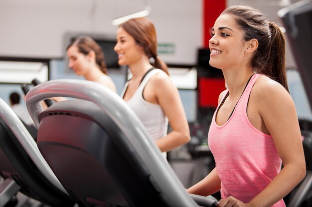 Schöne Gruppe junger Frauen, die auf einem Laufband im Fitnessstudio trainieren