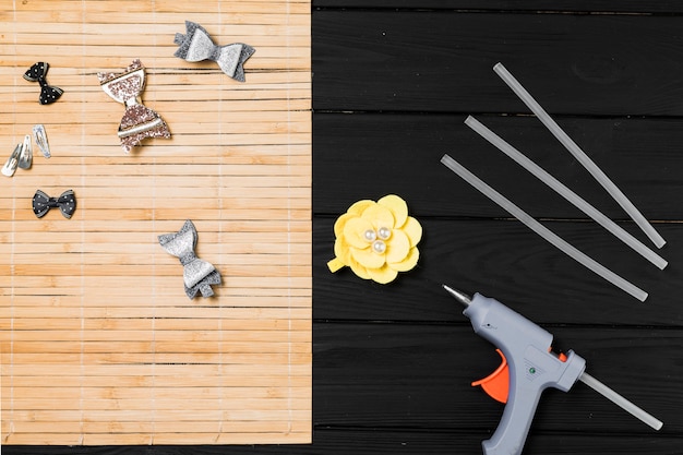 Kostenloses Foto schöne haarspange und heißklebepistole auf schwarzem holztisch