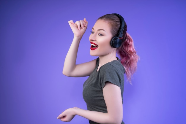 Schöne halbgedrehte Frau mit roten Lippen, die lächeln und die Musik genießen