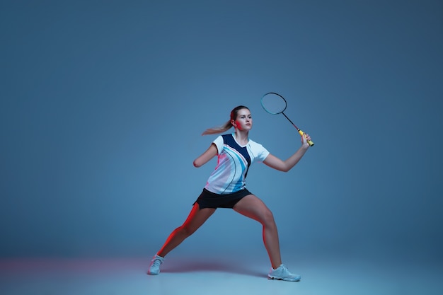 Schöne Handicapfrau, die im Badminton lokalisiert auf blauem Hintergrund im Neonlicht übt. Lebensstil integrativer Menschen, Vielfalt und Gleichheit. Sport, Aktivität und Bewegung. Copyspace für Anzeige.