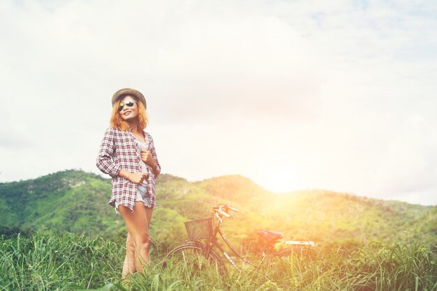 Schöne hipster Frau auf einer grünen Wiese mit der Natur ein stehendes