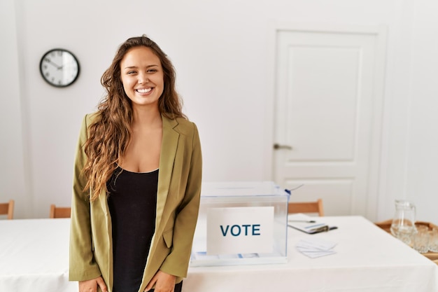 Kostenloses Foto schöne hispanische frau steht im wahlkampfraum mit einem glücklichen und kühlen lächeln im gesicht einer glücklichen person