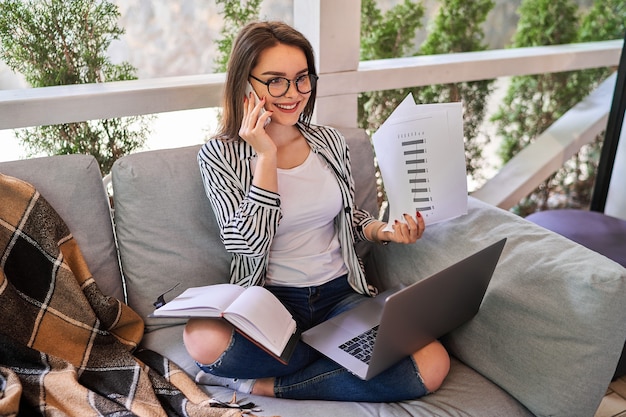 Schöne hübsche Frau, die zu Hause mit Laptop arbeitet.