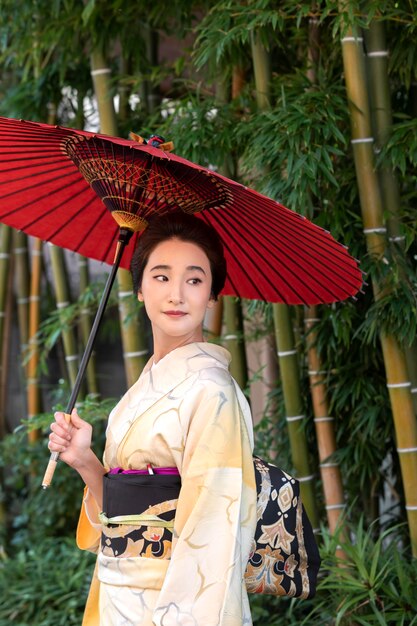 Schöne japanische Frau mit einem roten Regenschirm draußen