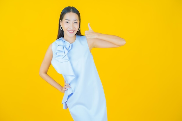 Schöne junge asiatische Frau des Porträts, die auf Gelb lächelt
