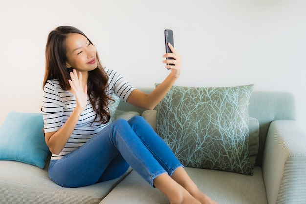 Schöne junge asiatische Frau des Porträts, die Handy verwendet oder spricht