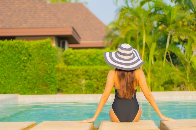Schöne junge asiatische Frau des Porträts, die sich im Urlaub am Pool im Resorthotel entspannt?