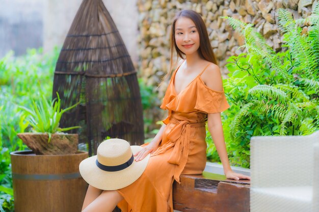 Schöne junge asiatische Frau des Porträts entspannen sich auf Stuhl um Garten