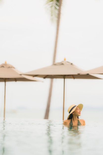Kostenloses Foto schöne junge asiatische frau des porträts entspannen sich im luxusaußenpool im strandurlaubsort fast seeozean