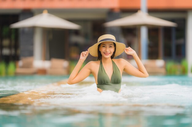 Schöne junge asiatische Frau des Porträts entspannen sich im Luxusaußenpool im Strandurlaubsort fast Seeozean
