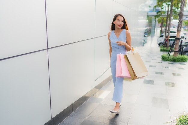 Schöne junge asiatische Frau des Porträts glücklich und Lächeln mit Einkaufstasche vom Kaufhaus