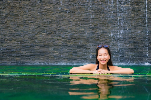 Schöne junge asiatische Frau des Porträts im Swimmingpool um Hotel und Erholungsort