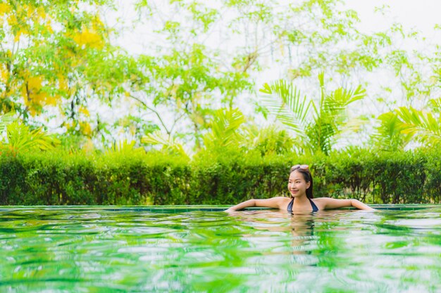 Schöne junge asiatische Frau des Porträts im Swimmingpool um Hotel und Erholungsort