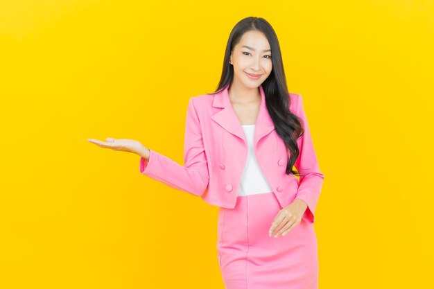 Schöne junge asiatische Frau des Porträts lächeln mit Aktion auf gelber Farbwand
