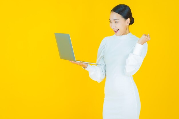 Schöne junge asiatische Frau des Porträts lächeln mit Computerlaptop auf lokalisiertem Hintergrund