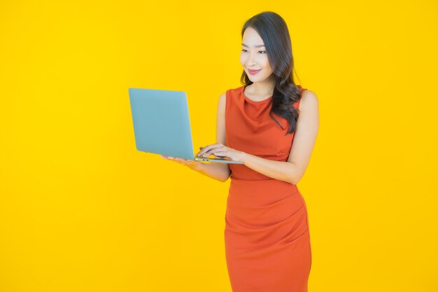 Schöne junge asiatische Frau des Porträts lächeln mit Computerlaptop auf lokalisiertem Hintergrund