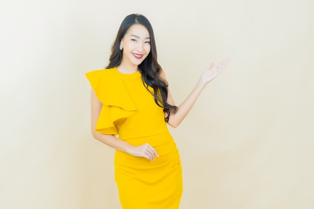 Schöne junge asiatische Frau des Porträts lächelt auf beige Wand