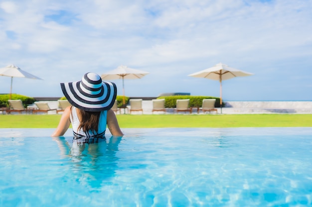 Schöne junge asiatische frau des porträts um swimmingpool