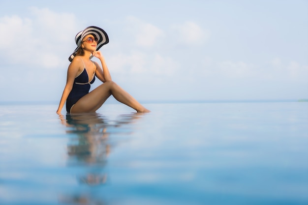 schöne junge asiatische Frau entspannen um Pool im Hotel Resort