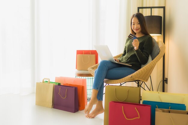 Schöne junge asiatische Frauen des Porträts, die Computerlaptop mit Kreditkarte für das on-line-Einkaufen verwenden