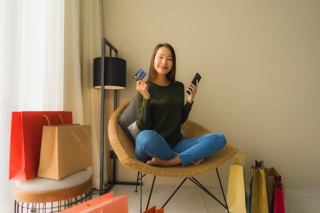 Schöne junge asiatische Frauen des Porträts, die Handy mit Kreditkarte für das on-line-Einkaufen verwenden