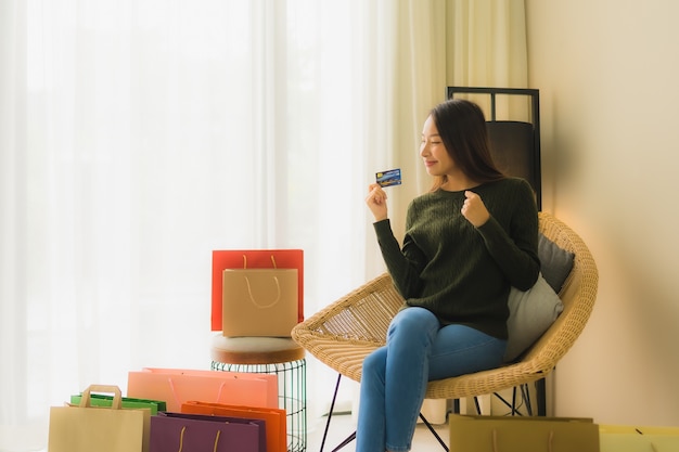 Schöne junge asiatische Frauen des Porträts, die Kreditkarte für das on-line-Einkaufen verwenden