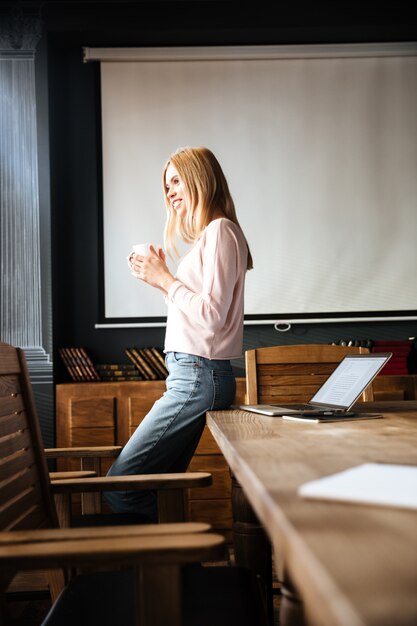 Schöne junge Dame, die im Caféarbeit mit Laptop steht.